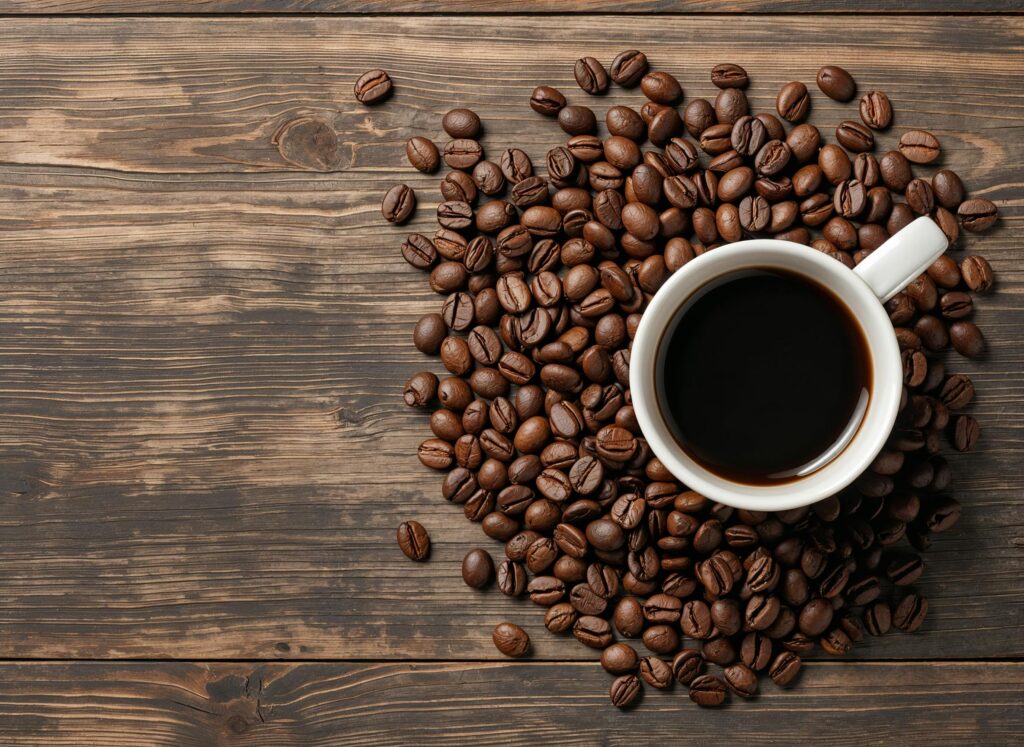 Home Aerial view of a coffee cup surrounded by roasted beans on wood.
